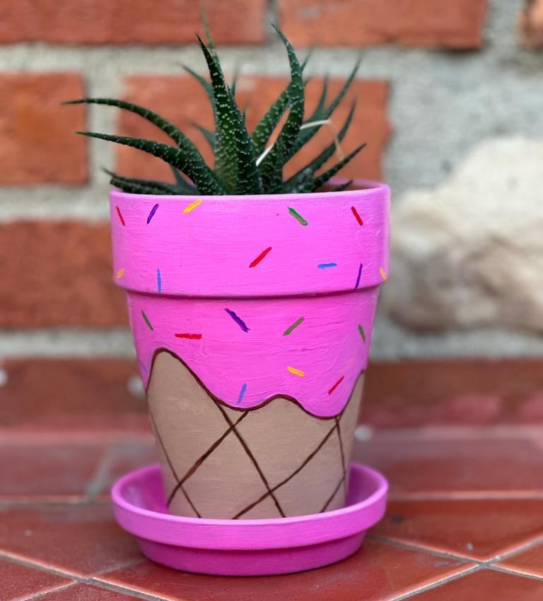 a terracota pot painted to look like an ice cream cone with strawberry ice cream covered with sprinkles
