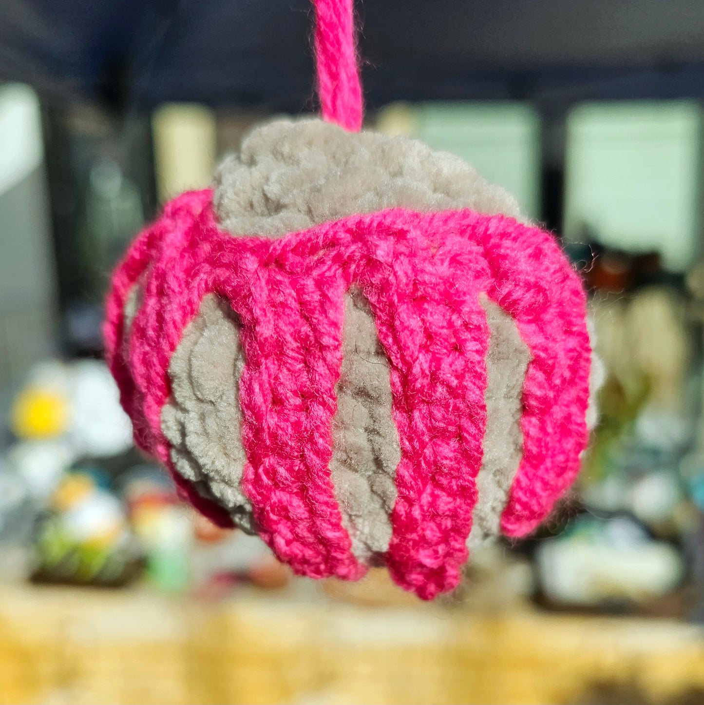 Mexican sweet bread shaped keychain made from beige plush yarn as the bread and the sugar frosting is made from bright fuchsia thin yarn. The keyring is attached to the sweet bread by yarn the same color as the sugar frosting.