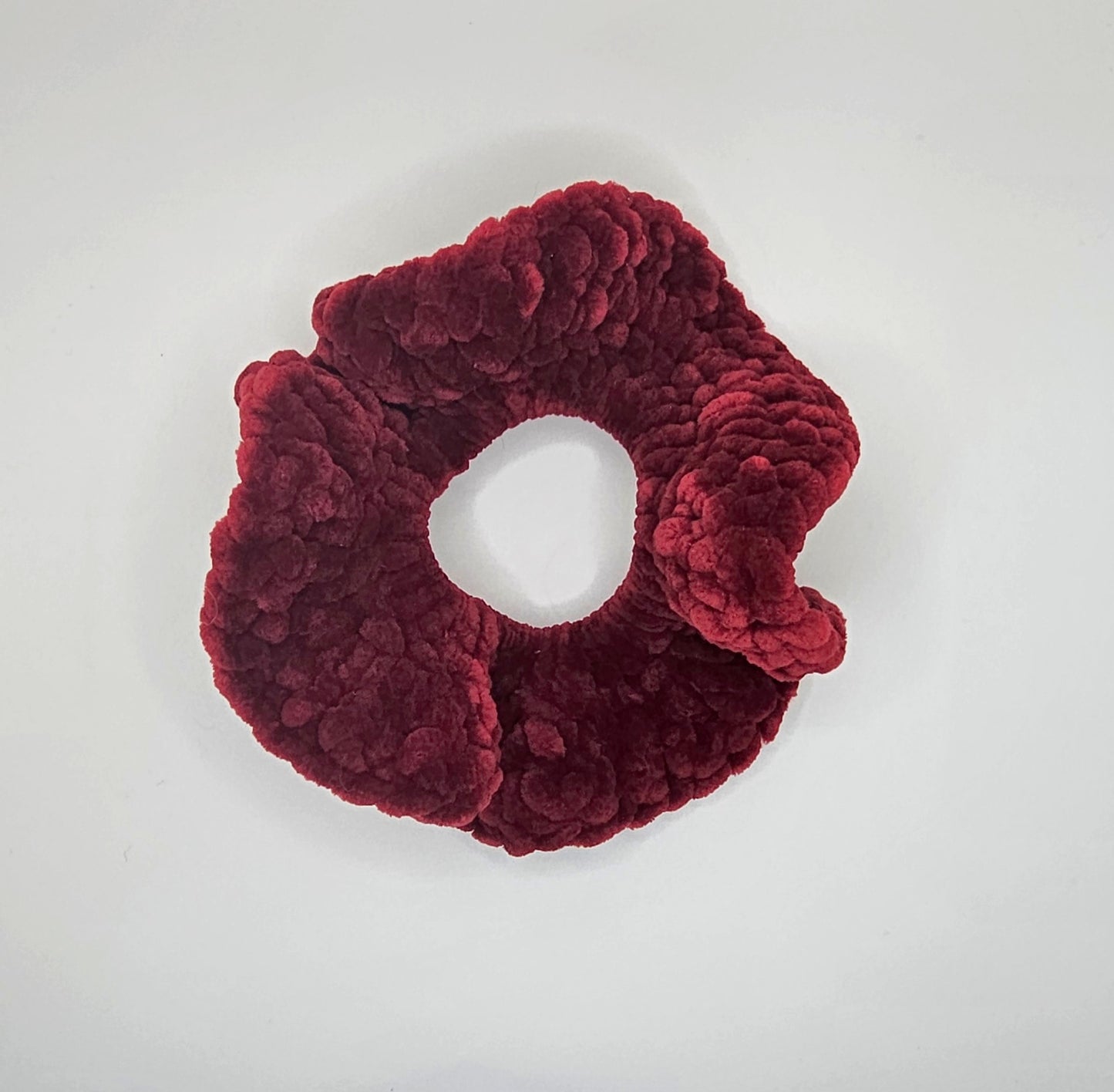 Velvet burgundy yarn crochet around a hair elastic to create a ruffly scrunchie.