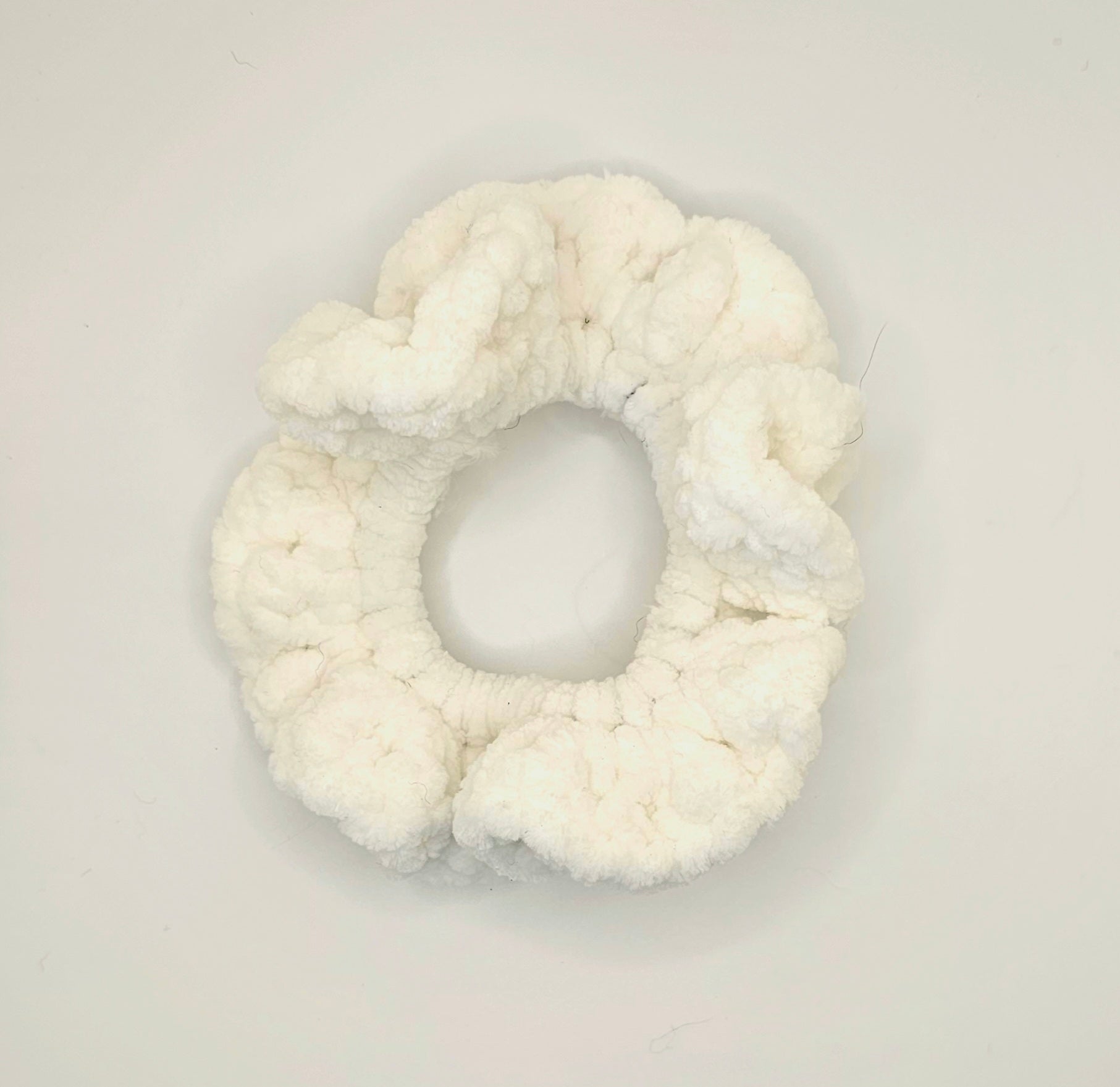 Velvet white yarn crochet around a hair elastic to create a ruffly scrunchie.