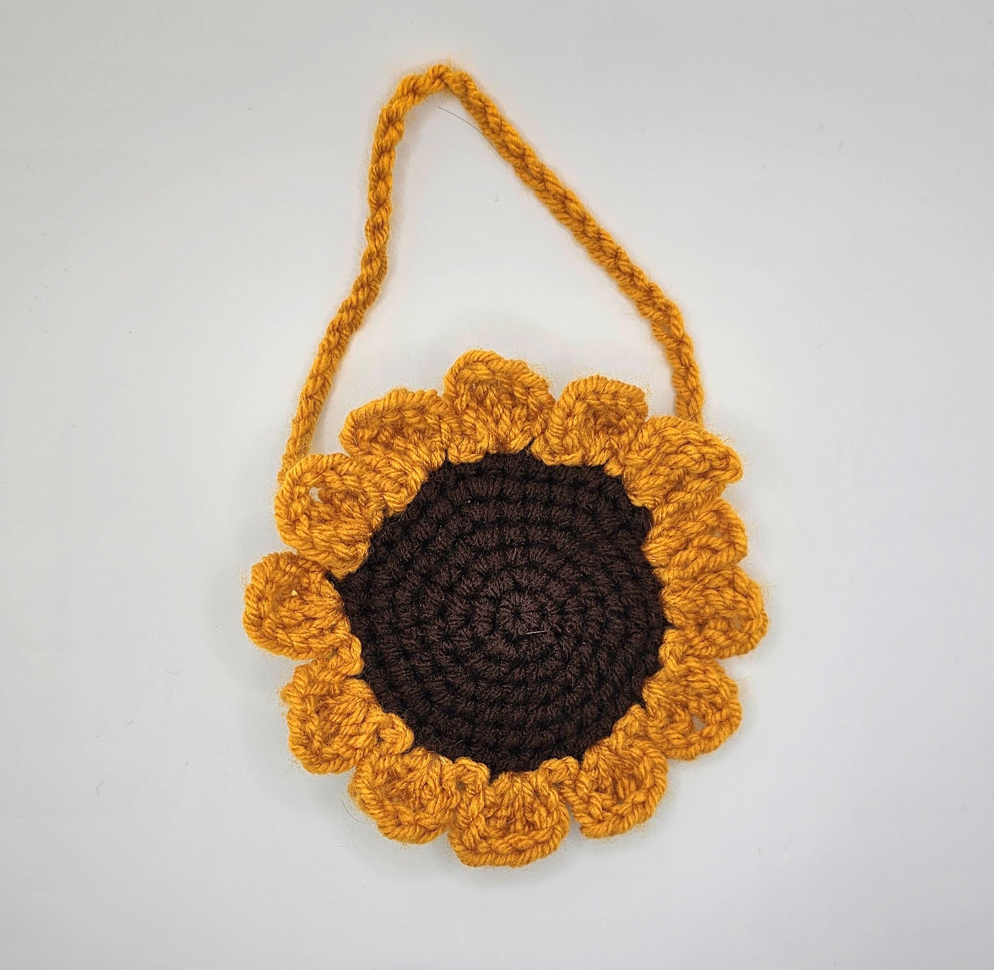 Crochet sunflower pouch. Front side. The center of the flower is made from brown yarn that spirals as it goes out. The petals are made from a marigold-yellow colored yarn--as well as the pouches handle.
