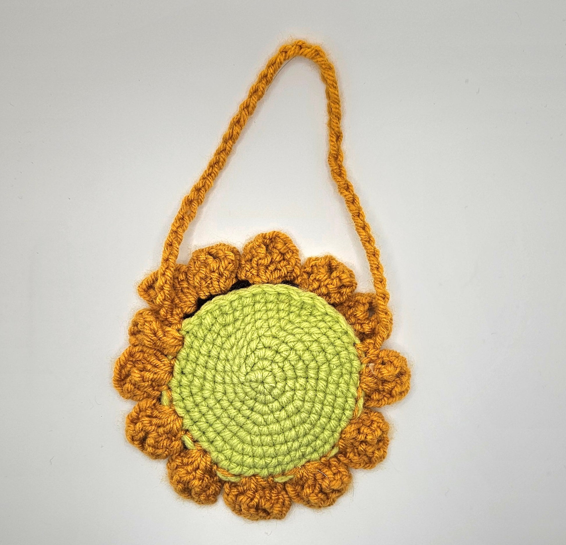 Crochet sunflower pouch. Back side. The center of the flower is made from light green yarn that spirals as it goes out. The petals are made from a marigold-yellow colored yarn--as well as the pouches handle.