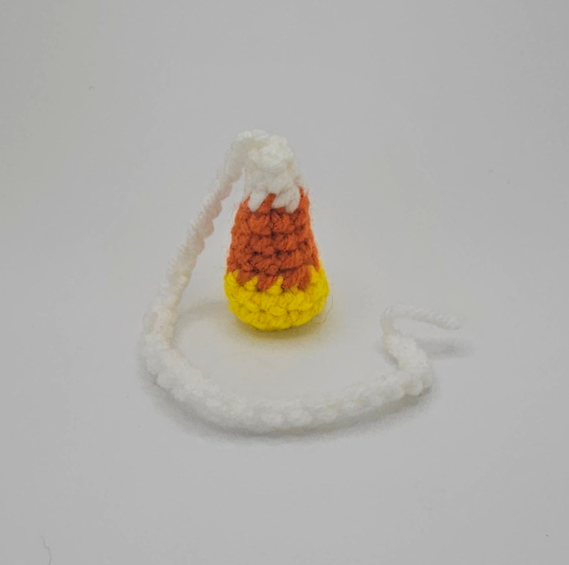 Yellow, orange and white yarn candy corn, crochet bookmark. The white top of the candy corn turns into a crochet braid.