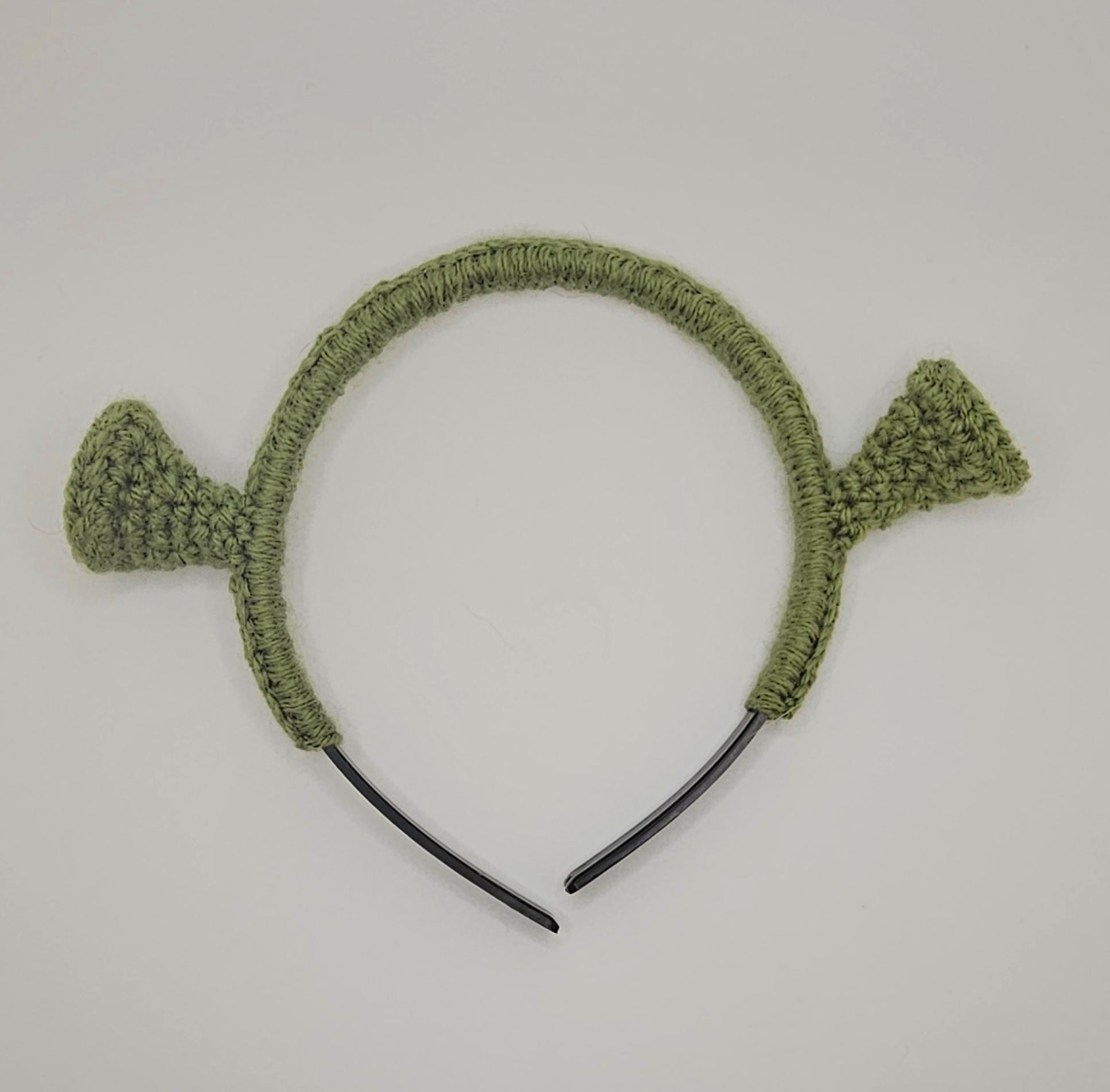 Olive green yarn over black plastic headband. The headband has crochet Shrek ears attached to the headband.
