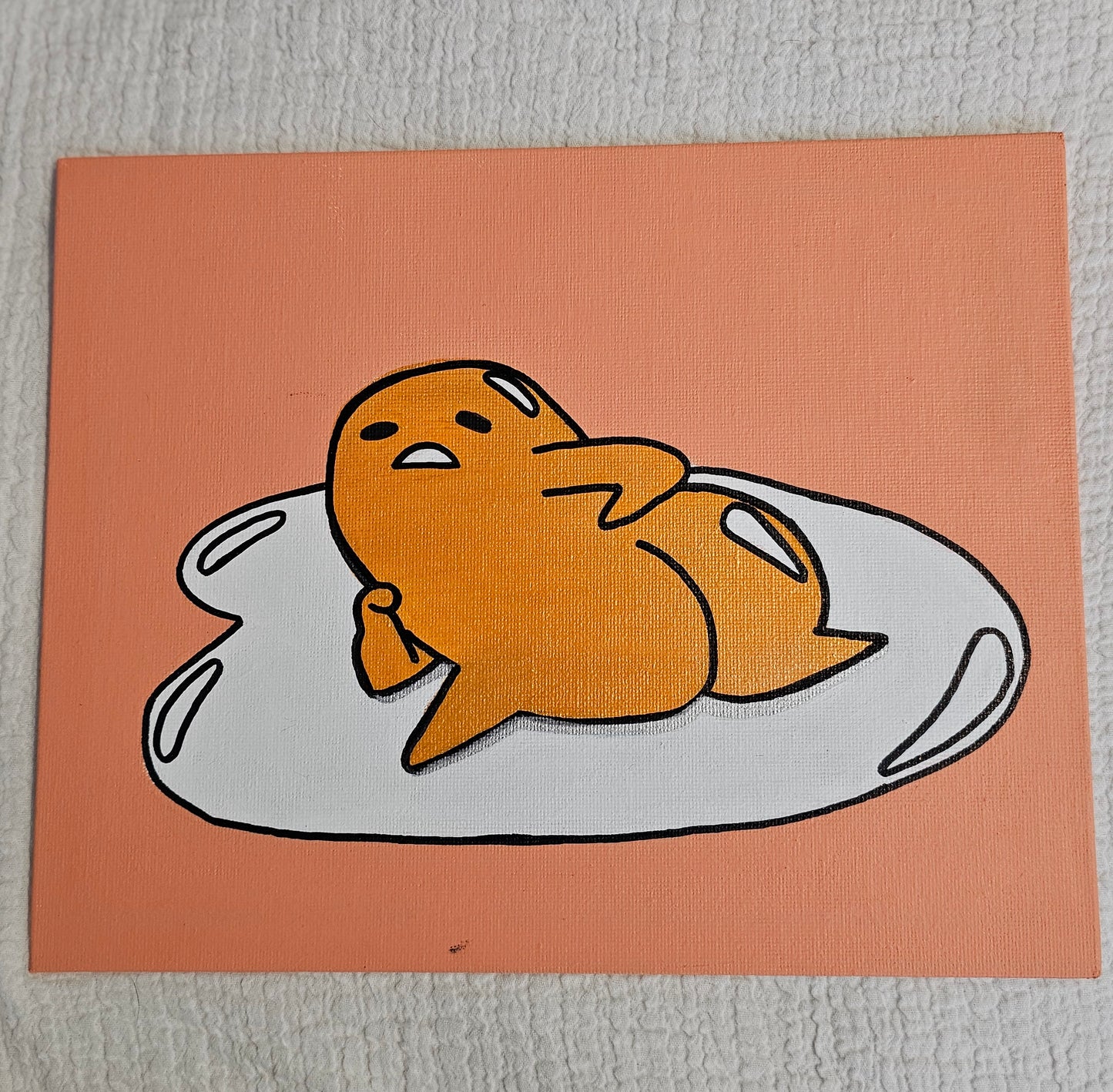 Canvas painting with a peach background and an image of a cheeky egg yolk laying on its egg white with a striking pose showing his butt cheeks. The egg yolk has a bored expression.